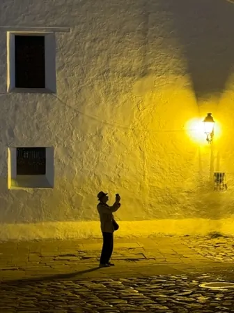 Homem parada em uma rua em frente a um lampião em Villa de Leyva, Colômbia. A imagem ganhou o grande prêmio do concurso de fotografia com iPhone