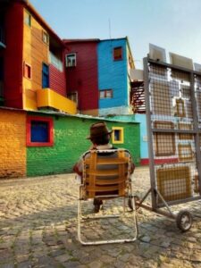 Vendedor de quadros sentando em frente a casa coloridas no bairro La Boca, Argentina. A imagem foi premiada no concurso de fotos com iPhone