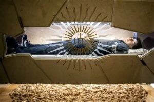 Santo Carlo Acutis em sua tumba em Assis usando tênis Nike e moletom North Sails