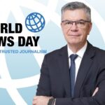 Jornalista Marcelo Rech com logo World News Day ao fundo