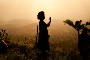 Mulher com telefone em fundo de sol poente em Belém, sede da COP30