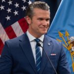 Pete Hegseth, chefe do Pentágono, com bandeiras ao fundo