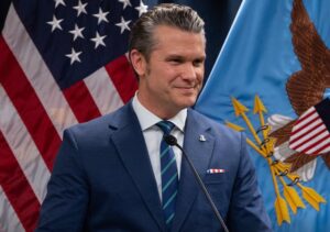 Pete Hegseth, chefe do Pentágono, com bandeiras ao fundo