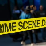 Faixa amarela crime scene com multidão ao fundo