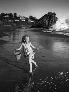Criança brincando na praia. A imagem em preto e branco foi premiada no iPhone Photography Awards 2026, categoria crianças
