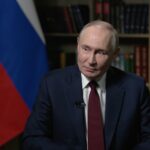 Vladimir Putin, presidente da Rússia, com bandeira e livros ao fundo