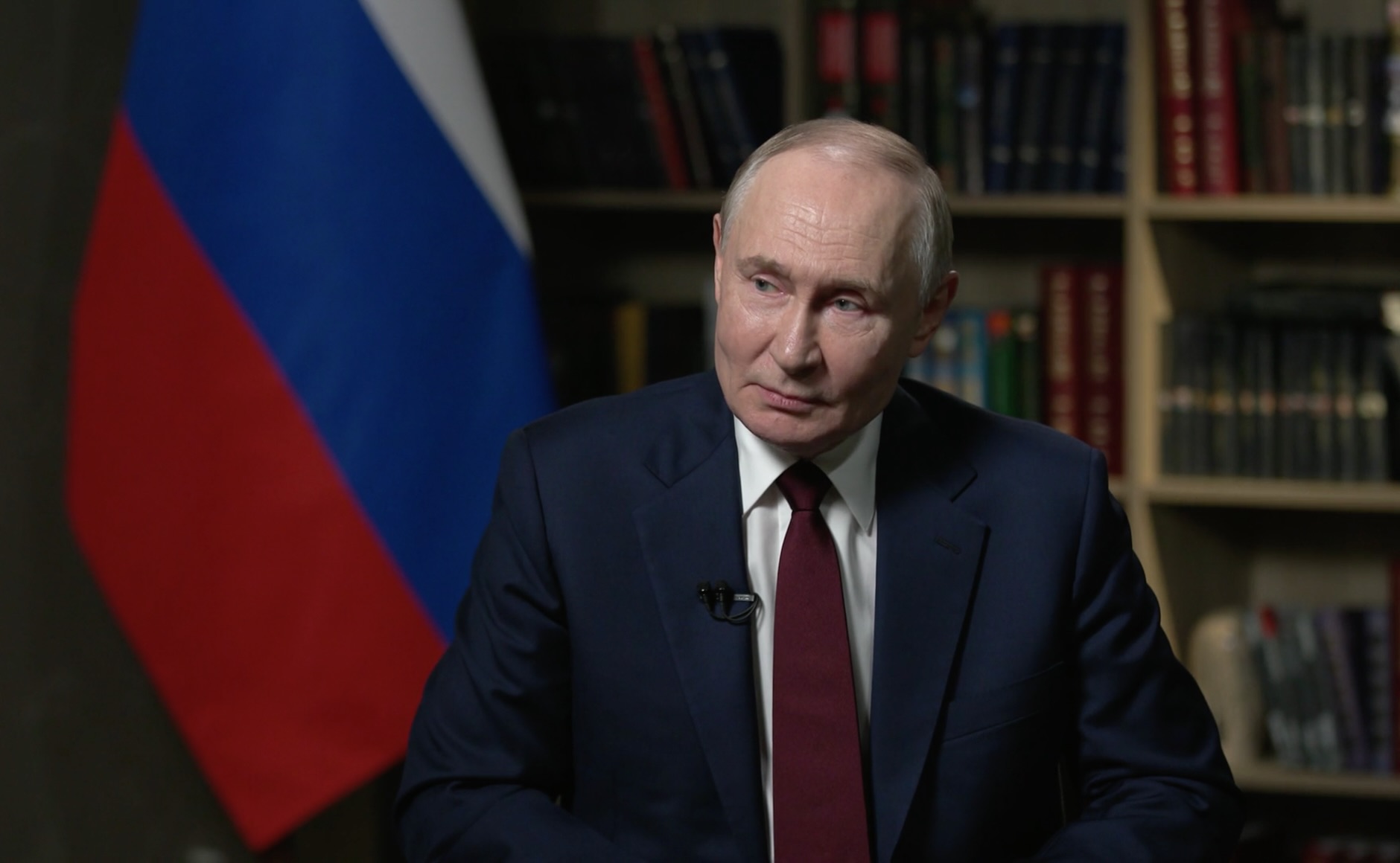 Vladimir Putin, presidente da Rússia, com bandeira e livros ao fundo