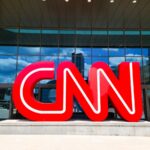 Logotipo da CNN em pedestal com prédio envidraçado ao fundo