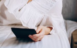 Mulher lendo no tablet deitada na cama