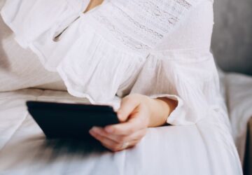 Mulher lendo no tablet deitada na cama