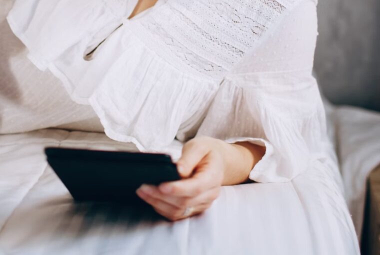 Mulher lendo no tablet deitada na cama